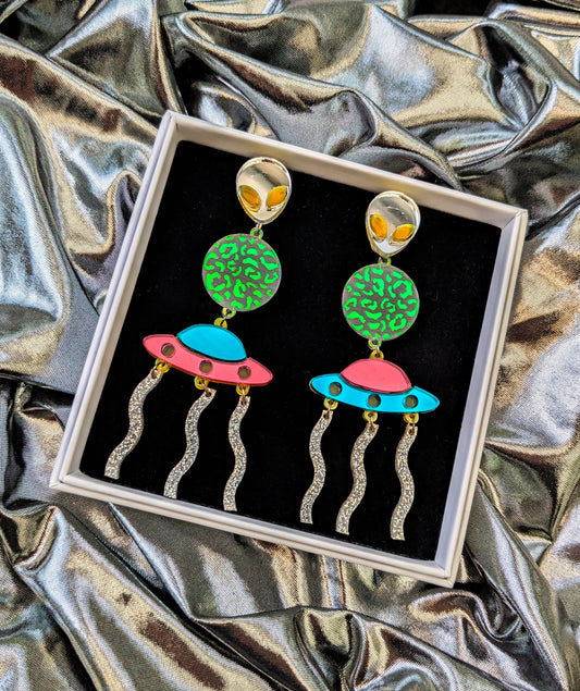 Silver Lasers Statement Earrings with silver and neon green acrylic Alien, a transparent planet with iridescent mermaid acrylic leopard print detailing, Mismatching Pink and Turquoise Mirrored Acrylic Spaceship, and silver sparkly acrylic laser beams